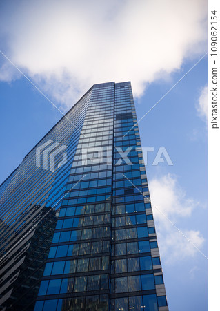 Vertical photo of the facade of a narrow wall of a skyscraper. Typical modern glass building for business and residential purposes 109062154