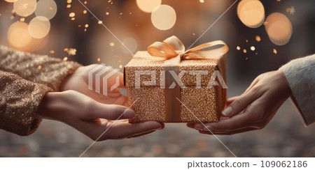 Hands of a woman with a New Year's gift box against a Christmas backdrop Hands of a woman with a New Year's gift box against a Christmas backdrop 109062186