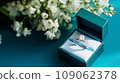 wedding ring in beautiful packaging with white flowers on turquoise background, marriage proposal 109062378