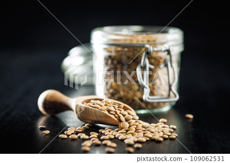 Uncooked lentil legumes in wooden scoop on black table. 109062531