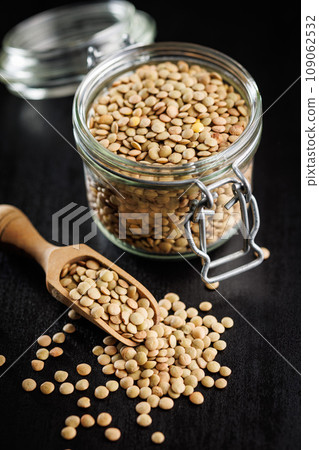 Uncooked lentil legumes in jar on black table. 109062532