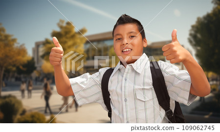 Excited Young Hispanic Boy Wearing a Backpack Giving Two Thumbs Up on Campus. Excited Young Hispanic Boy Wearing a Backpack Giving Two Thumbs Up on Campus. 109062745