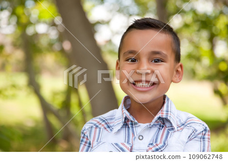 Smiling Young Hispanic Boy Outdoors Amongst the Trees. 109062748