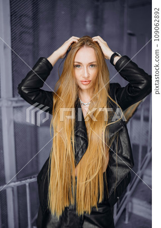 Beautiful young red-haired long-haired woman in black leather shirt 109062892