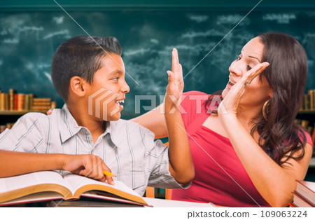 Latina School Teacher High Fiving a Young Hispanic Boy in the Classroom. Latina School Teacher High Fiving a Young Hispanic Boy in the Classroom. 109063224