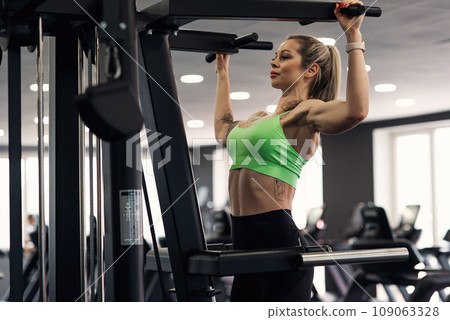 Woman doing pull ups exercise training arms and back in the gym. Upper body training. 109063328