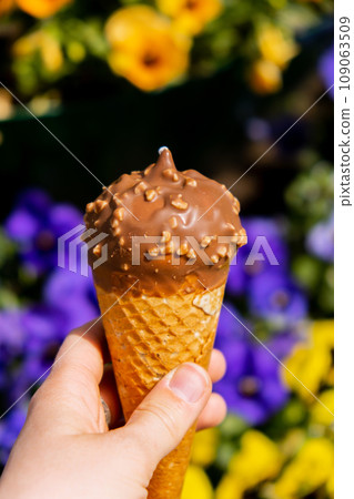 Female hand holding delicious american vanilla chocolate ice cream. Tasty homemade icecream Gelato in the waffle cone. Gluten free vegan dairy free 109063509