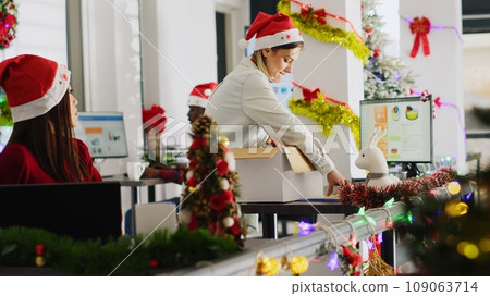 Pissed employee packs desk belongings and steals Christmas office ornaments on last day at work to feel better. Vengeful woman getting fired from job during layoffs, delighted about retribution 109063714