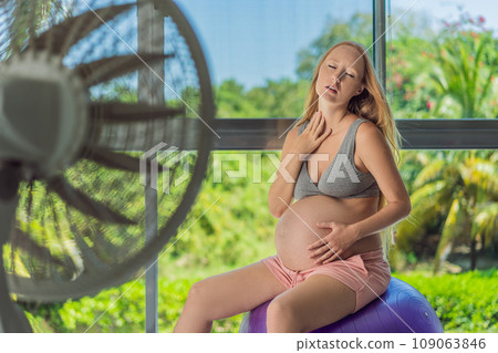 A pregnant woman seeks relief from an abnormal heatwave by using a fan, ensuring her comfort and well-being during sweltering conditions 109063846