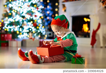 Kids at Christmas tree. Children open presents 109064026