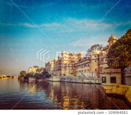 Vintage retro hipster style travel image of romantic India luxury tourism concept background - Udaipur City Palace and Lake Pichola. Udaipur, Rajasthan, India with grunge texture overlaid Vintage retro hipster style travel image of romantic India luxury tourism concept background - Udaipur City Palace and Lake Pichola. Udaipur, Rajasthan, India with grunge texture overlaid 109064881