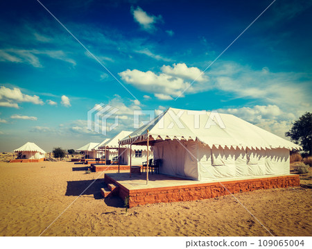 Vintage retro hipster style travel image of luxury tents in desert. Jaisalmer, Rajasthan, India 109065004