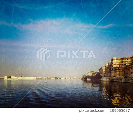 Vintage retro hipster style travel image of romantic India luxury tourism concept background - Udaipur City Palace, Lake Palace and Lake Pichola with grunge texture overlaid. Udaipur, Rajasthan, India Vintage retro hipster style travel image of romantic India luxury tourism concept background - Udaipur City Palace, Lake Palace and Lake Pichola with grunge texture overlaid. Udaipur, Rajasthan, India 109065027