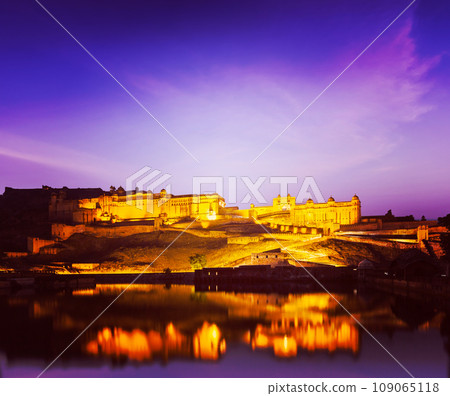 Vintage retro hipster style travel image of Amer Fort (Amber Fort) illuminated at night - one of principal attractions in Jaipur, Rajastan, India refelcting in Maota lake in twilight Vintage retro hipster style travel image of Amer Fort (Amber Fort) illuminated at night - one of principal attractions in Jaipur, Rajastan, India refelcting in Maota lake in twilight 109065118
