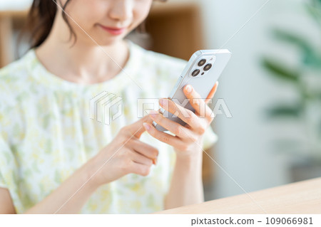 一位女士正在檢查她的智慧型手機。 （部分） 109066981