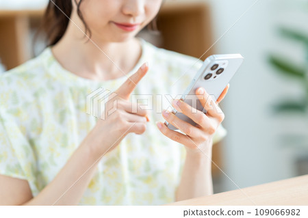 一位女士正在檢查她的智慧型手機。 （部分） 109066982