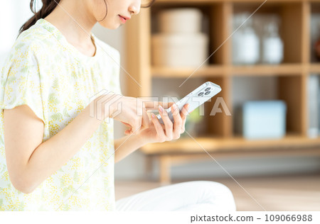 一位女士正在檢查她的智慧型手機。 （部分） 109066988