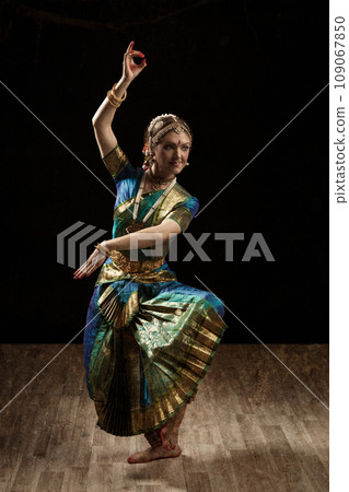 Vintage retro style image of young beautiful woman dancer exponent of Indian classical dance Bharatanatyam in Shiva pose Vintage retro style image of young beautiful woman dancer exponent of Indian classical dance Bharatanatyam in Shiva pose 109067850
