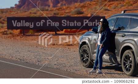 Young woman on a road trip through the desert leaning against her car Young woman on a road trip through the desert leaning against her car 109068292