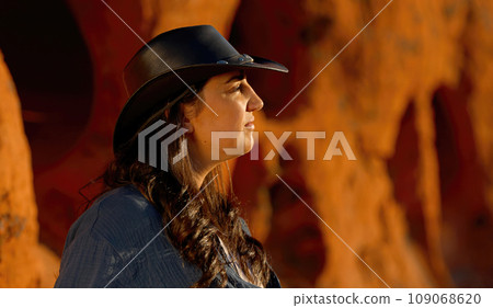 Cowgirl relaxing on a red rock in the desert of Arizona 109068620