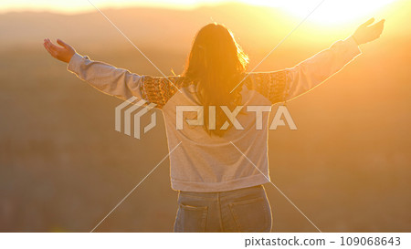 Young woman standing on a cliff at Grand Canyon and raising her arms from a feeling of infinite 109068643