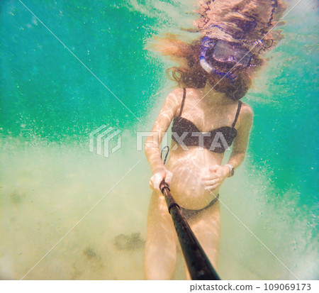 In an ethereal underwater scene, a pregnant woman gracefully floats, embodying the beauty of maternity beneath the tranquil surface of the sea In an ethereal underwater scene, a pregnant woman gracefully floats, embodying the beauty of maternity beneath the tranquil surface of the sea 109069173