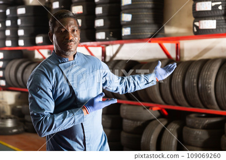 Portrait of serious auto mechanic in front of car tires Portrait of serious auto mechanic in front of car tires 109069260