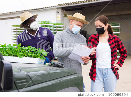 Girl in mask discussing with workers delivery of seedlings 109069294