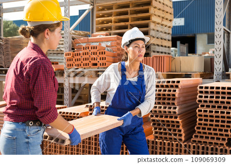 Women carrying flat hollow clay brick in outdoor warehouse 109069309