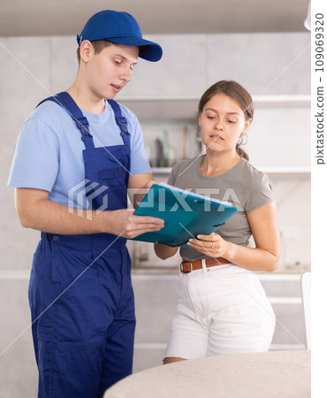 Male employee of repair team gives girl client documents . Male employee of repair team gives girl client documents . 109069320
