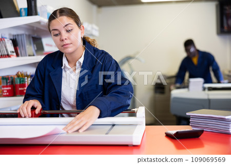 Work in printing house - woman cuts paper with professional cutter 109069569