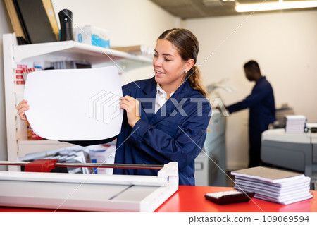 Portrait of an attentive woman checking quality of printing in printing house 109069594