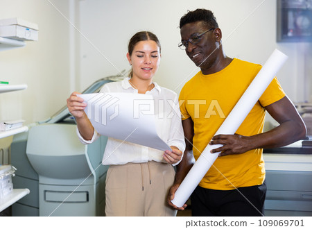 Man and woman check the print quality together in computer room Man and woman check the print quality together in computer room 109069701