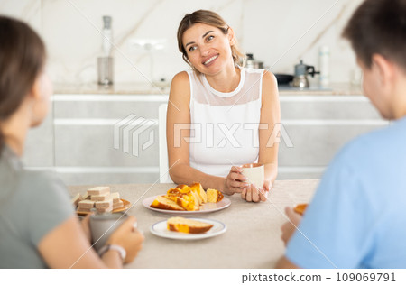 Mother having good time with adult children drinking tea in live room Mother having good time with adult children drinking tea in live room 109069791