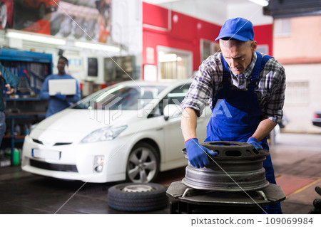 Professional american car mechanic changing the wheel Professional american car mechanic changing the wheel 109069984