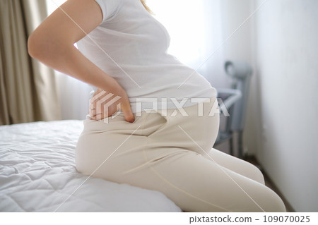 Pregnant woman in bedroom experiences aching pain in body. Lady with determination rocks body in circles relieving from persistent discomfort crop body 109070025