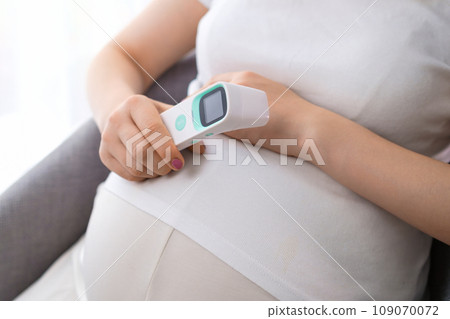 Pregnant woman holding a thermometer in her hand. Health care concept. Illness during pregnancy Pregnant woman holding a thermometer in her hand. Health care concept. Illness during pregnancy 109070072