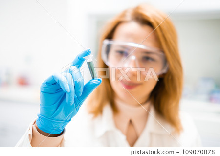 Chemist holding a test tube with blue solution. 109070078