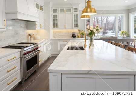 Interior of modern luxurious kitchen classic style. White cabinets with gilded handles, kitchen island with white marble countertop, built-in home appliances, vintage pendant lights. Home design. Interior of modern luxurious kitchen classic style. White cabinets with gilded handles, kitchen island with white marble countertop, built-in home appliances, vintage pendant lights. Home design. 109072751