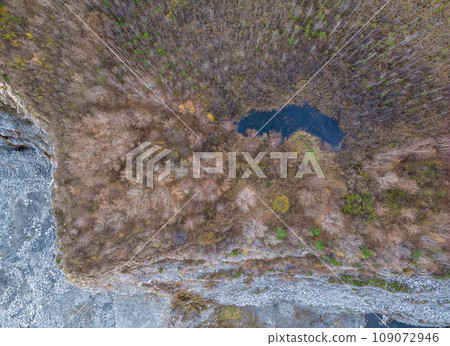 Colorful autumn forest with trees on the shore of a blue lake - top aerial view. 109072946