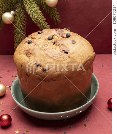 Christmas Panettone Italian Cake On Red Background with Christmas Toys, Decorations. Fruitcake Originally From Italy, Sweet bread. Milan Baked Dessert. Vertical plane. Christmas Panettone Italian Cake On Red Background with Christmas Toys, Decorations. Fruitcake Originally From Italy, Sweet bread. Milan Baked Dessert. Vertical plane. 109073234