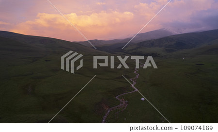 Pink-purple sunset in mountains with green fields Pink-purple sunset in mountains with green fields 109074189