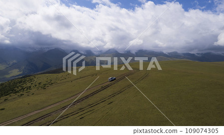 A white SUV rides in the mountains through fields 109074305