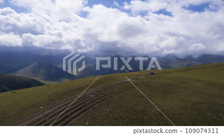 A white SUV rides in the mountains through fields 109074311