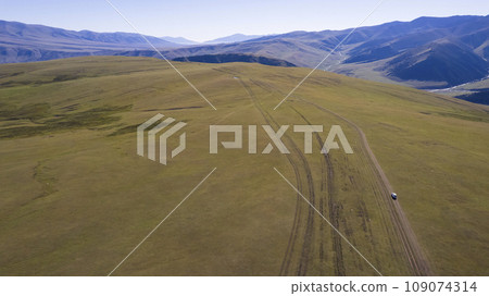 A white SUV rides in the mountains through fields A white SUV rides in the mountains through fields 109074314