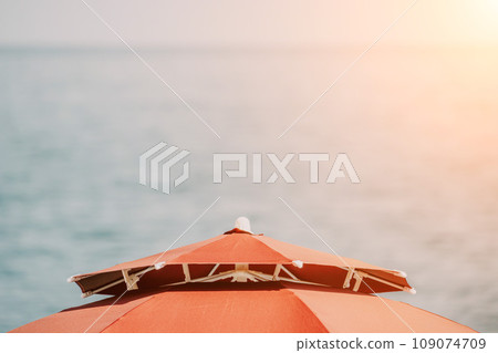 Red Beach Umbrella on the Background of the Blue Sea Ocean. Beach Landscape. Summer travel and holidays concept. 109074709