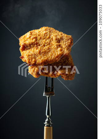 Hot fried schnitzel on a fork. 109075033