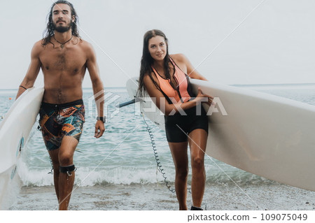 Sea woman and man on sup. Silhouette of happy young woman and man, surfing on SUP board, confident paddling through water surface. Idyllic sunset. Active lifestyle at sea or river. Sea woman and man on sup. Silhouette of happy young woman and man, surfing on SUP board, confident paddling through water surface. Idyllic sunset. Active lifestyle at sea or river. 109075049