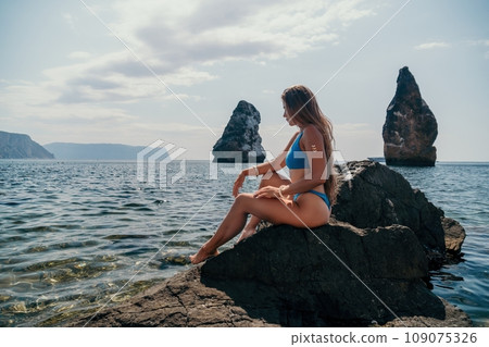 Woman summer travel sea. Happy tourist enjoy taking picture outdoors for memories. Woman traveler posing on the beach at sea surrounded by volcanic mountains, sharing travel adventure journey Woman summer travel sea. Happy tourist enjoy taking picture outdoors for memories. Woman traveler posing on the beach at sea surrounded by volcanic mountains, sharing travel adventure journey 109075326