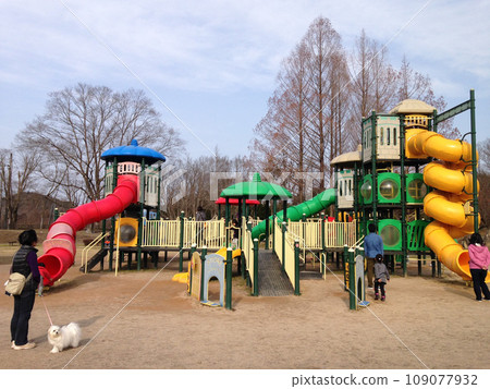 Parents and children playing with large playground equipment in the park and their dog 109077932